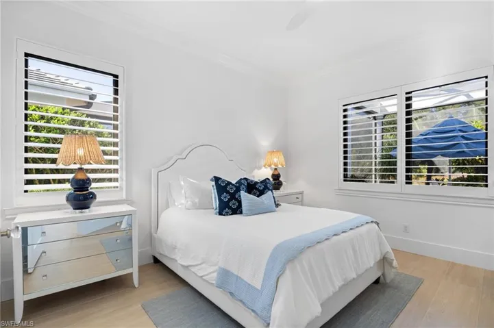 Bedroom featuring ornamental molding, light wood-style flooring, and a ceiling fan