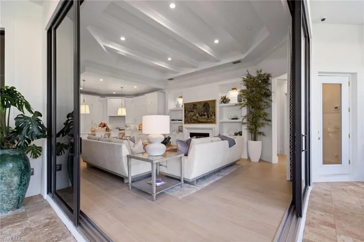 Living area featuring a fireplace, beam ceiling, wood tiled floors, and ornamental molding