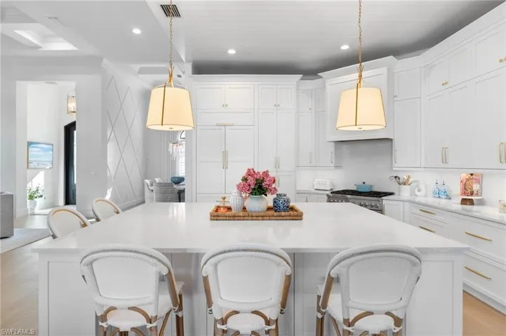 Kitchen with a breakfast bar area, light wood-style floors, white cabinetry, stainless steel gas range, and a center island