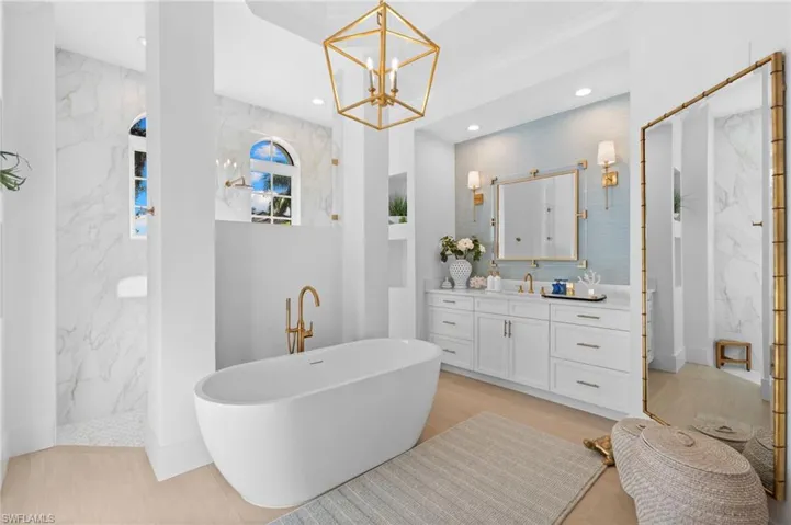 Bathroom featuring a marble finish shower, vanity, a soaking tub, a chandelier, and light wood finished floors