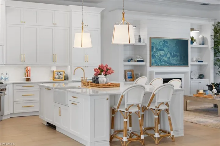 Kitchen with white cabinetry, hanging light fixtures, light wood-style flooring, and an island with sink