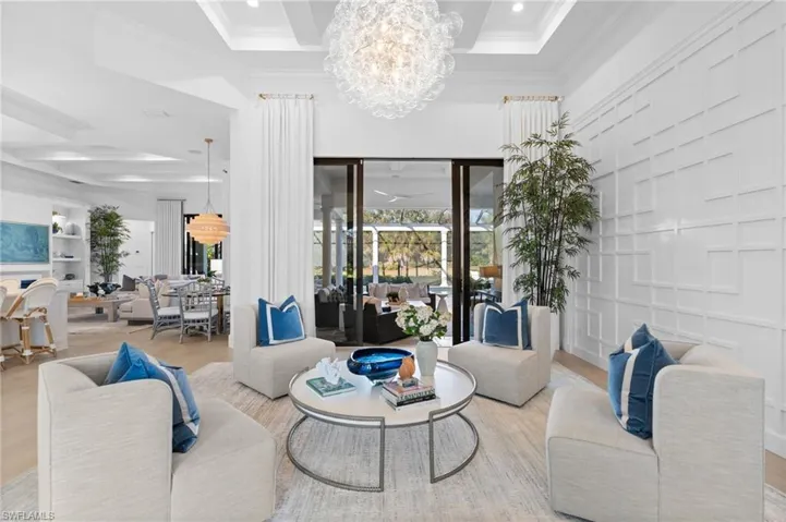 Living area featuring hanging lights, ornamental molding, coffered ceiling, and wood finished floors