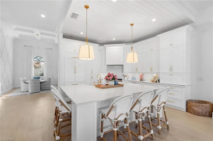 Kitchen featuring a kitchen breakfast bar, ornamental molding, light wood-style flooring, white cabinetry, and a spacious island