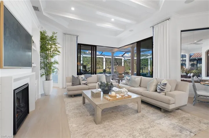 Living room with a sunroom, a fireplace, light wood finished floors, ornamental molding, and recessed lighting