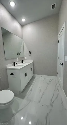 Bathroom featuring vanity, light marble finish flooring, and recessed lighting