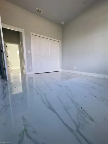 Unfurnished bedroom with light marble finish floors and a closet