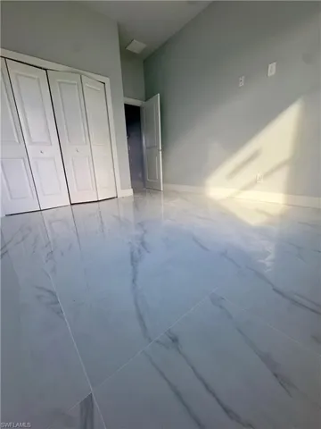 Unfurnished bedroom featuring marble look tile flooring and a closet