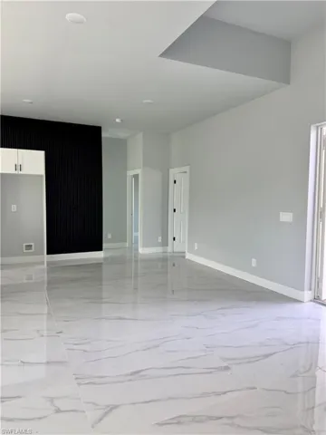 Unfurnished room featuring light marble finish floors and baseboards