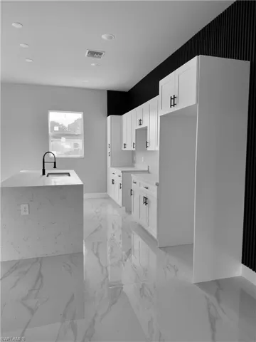 Kitchen featuring white cabinetry, light marble finish flooring, light stone countertops, and recessed lighting