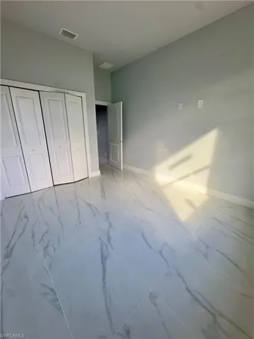 Unfurnished bedroom featuring marble finish flooring and a closet