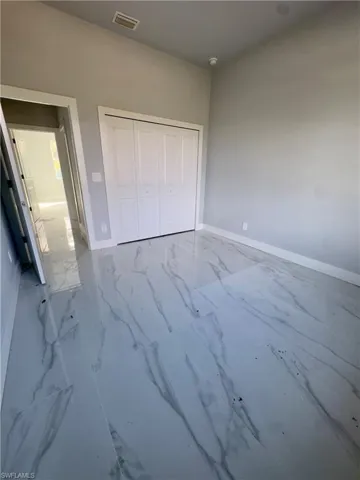 Unfurnished bedroom featuring marble look tile flooring and a closet