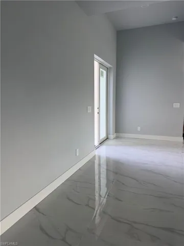 Spare room with light marble finish flooring and baseboards