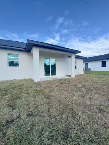Rear view of house with stucco siding, a yard, and a patio area