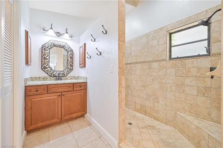 Full bath with vanity, walk in shower, and light tile patterned floors