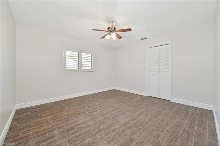 Empty room featuring dark wood-style flooring and a ceiling fan