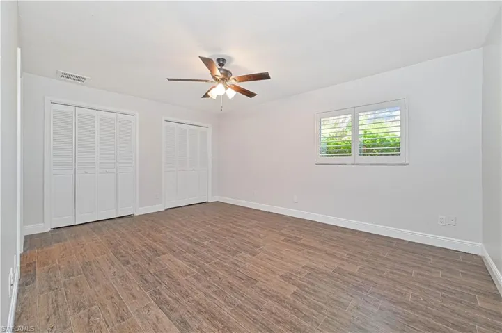 Unfurnished bedroom featuring multiple closets, wood finish floors, and a ceiling fan