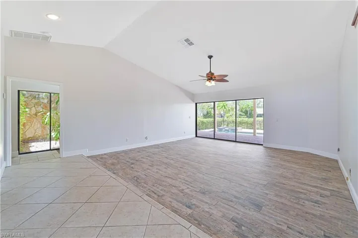 Empty room with light wood-style floors, ceiling fan, high vaulted ceiling, and recessed lighting