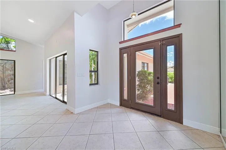 Entrance foyer with a towering ceiling, light tile patterned floors, and healthy amount of natural light