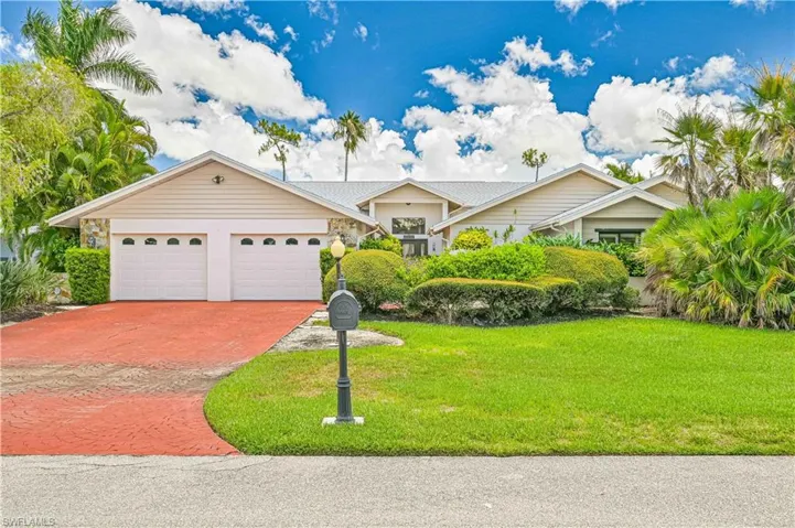 View of front of home with decorative driveway, a front lawn, and an attached garage