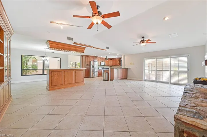 Unfurnished living room featuring light tile patterned flooring, plenty of natural light, vaulted ceiling, a chandelier, and recessed lighting
