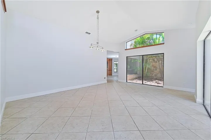 Unfurnished room featuring high vaulted ceiling and light tile patterned floors