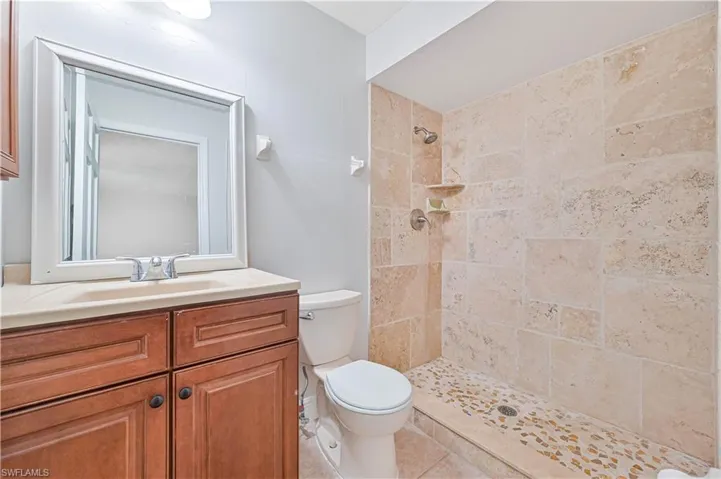 Bathroom featuring tiled shower, vanity, and light tile patterned flooring