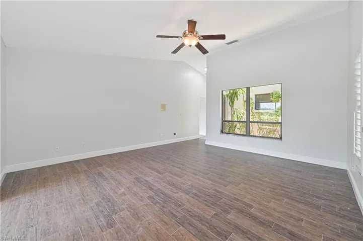 Spare room with dark wood-style flooring, vaulted ceiling, and ceiling fan
