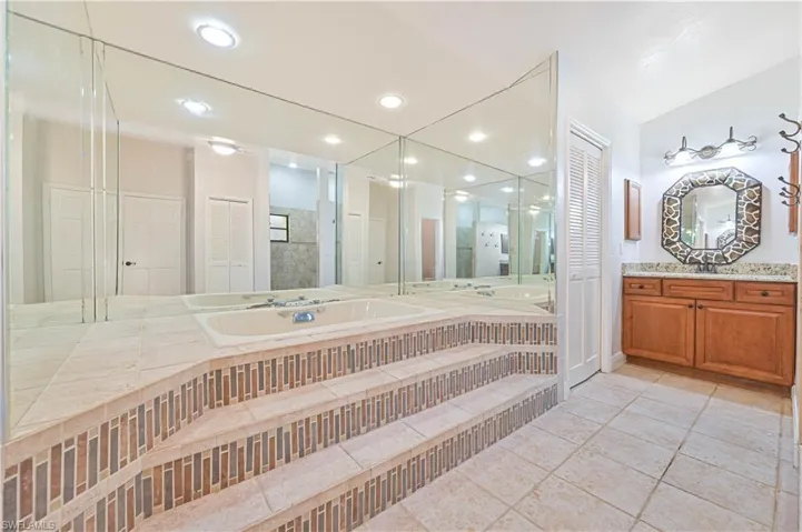 Full bathroom with vanity, recessed lighting, light tile patterned floors, a garden tub, and a closet