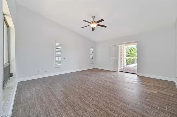 Spare room with wood tiled floors, a ceiling fan, and high vaulted ceiling