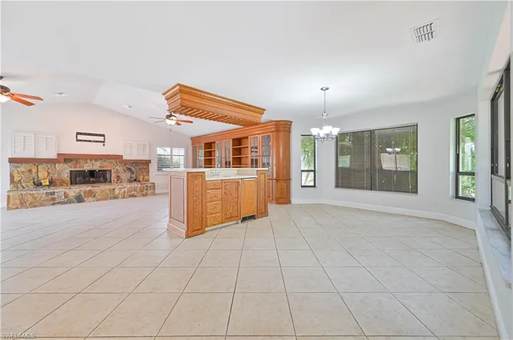 Kitchen featuring open floor plan, light countertops, light tile patterned floors, pendant lighting, and vaulted ceiling