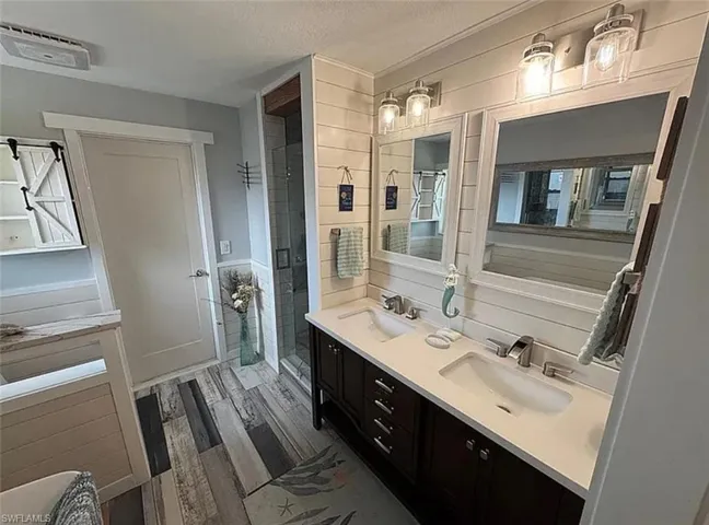 Kitchen with dark cabinets, decorative backsplash, wood finished floors, and dishwasher