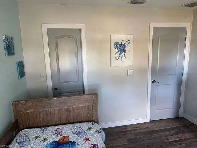 Bedroom featuring a barn door, dark wood-style flooring, and ceiling fan
