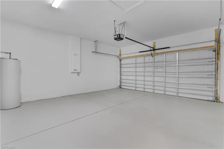 Garage featuring water heater, a garage door opener, and electric panel