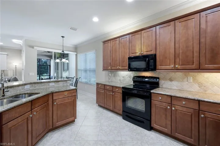 Open kitchen with wood cabinetry and granite countertops, a separate pantry (not shown), lots of counter space and storage, a breakfast bar and an adjoining, dedicated eat-in kitchen area.