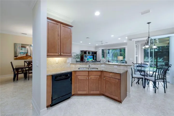 Open kitchen with wood cabinetry and granite countertops, a separate pantry (not shown), lots of counter space and storage, a breakfast bar and an adjoining, dedicated eat-in kitchen area.