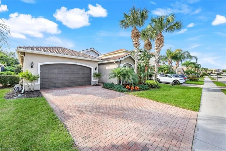 Front of home with brick paver driveway.