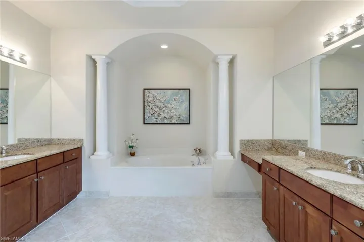 Master bathroom with his & her granite countertop vanities, shower (not shown), tub and W/C (not shown).