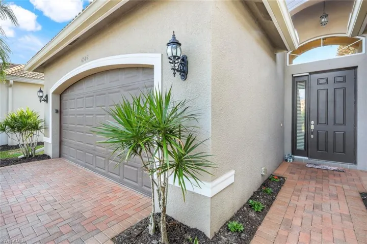 Front entryway with brick pavers and a two car garage.