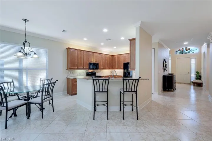 Open kitchen with wood cabinetry and granite countertops, a separate pantry (not shown), lots of counter space and storage, a breakfast bar and an adjoining, dedicated eat-in kitchen area.