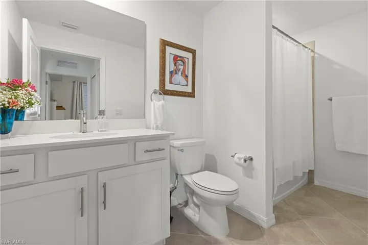 Bathroom with vanity, shower / bath combo, and light tile patterned floors