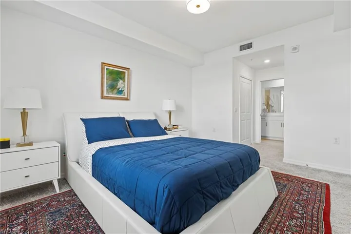 Carpeted bedroom featuring ensuite bathroom and baseboards