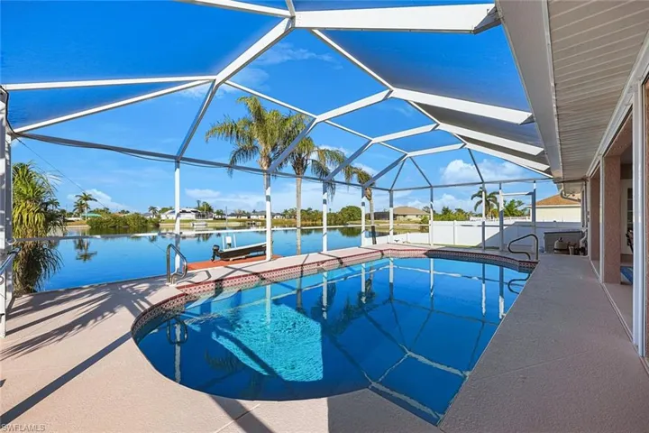 View of pool featuring glass enclosure, a water view, a patio, and a boat dock