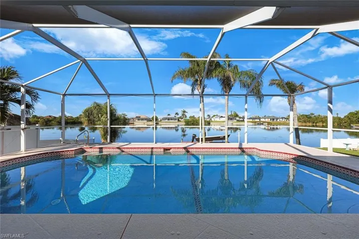 View of pool featuring glass enclosure, a dock, and a water view