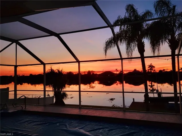 Pool at dusk featuring a water view and a lanai