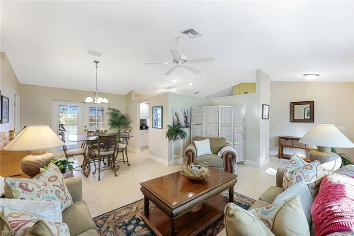Living room with ceiling fan with notable chandelier and lofted ceiling