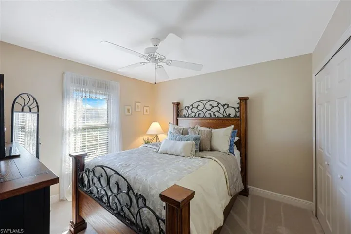 Carpeted bedroom with ceiling fan and a closet