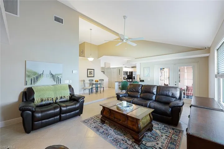Living room featuring ceiling fan, light tile patterned floors, high vaulted ceiling, and french doors
