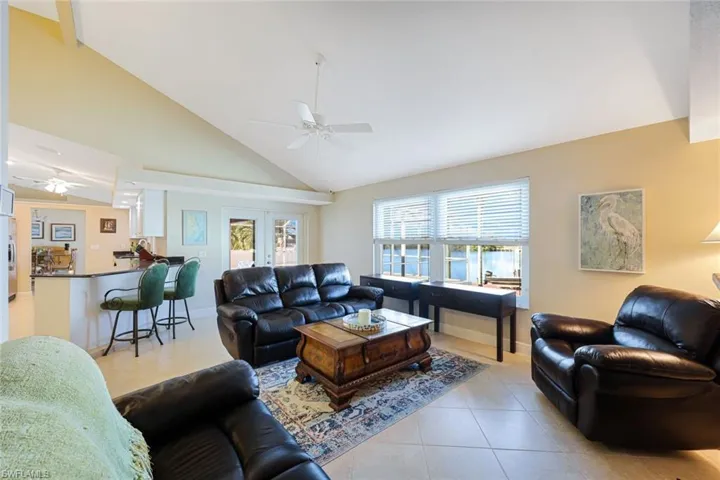 Tiled living room with french doors, high vaulted ceiling, and ceiling fan