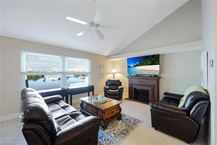 Living room with ceiling fan, light tile patterned floors, and high vaulted ceiling