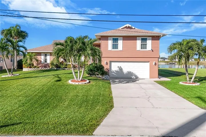 View of front facade featuring a water view, a garage, and a front lawn